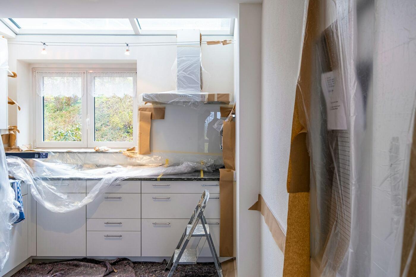 Kitchen under renovation with cabinets covered in protective sheets