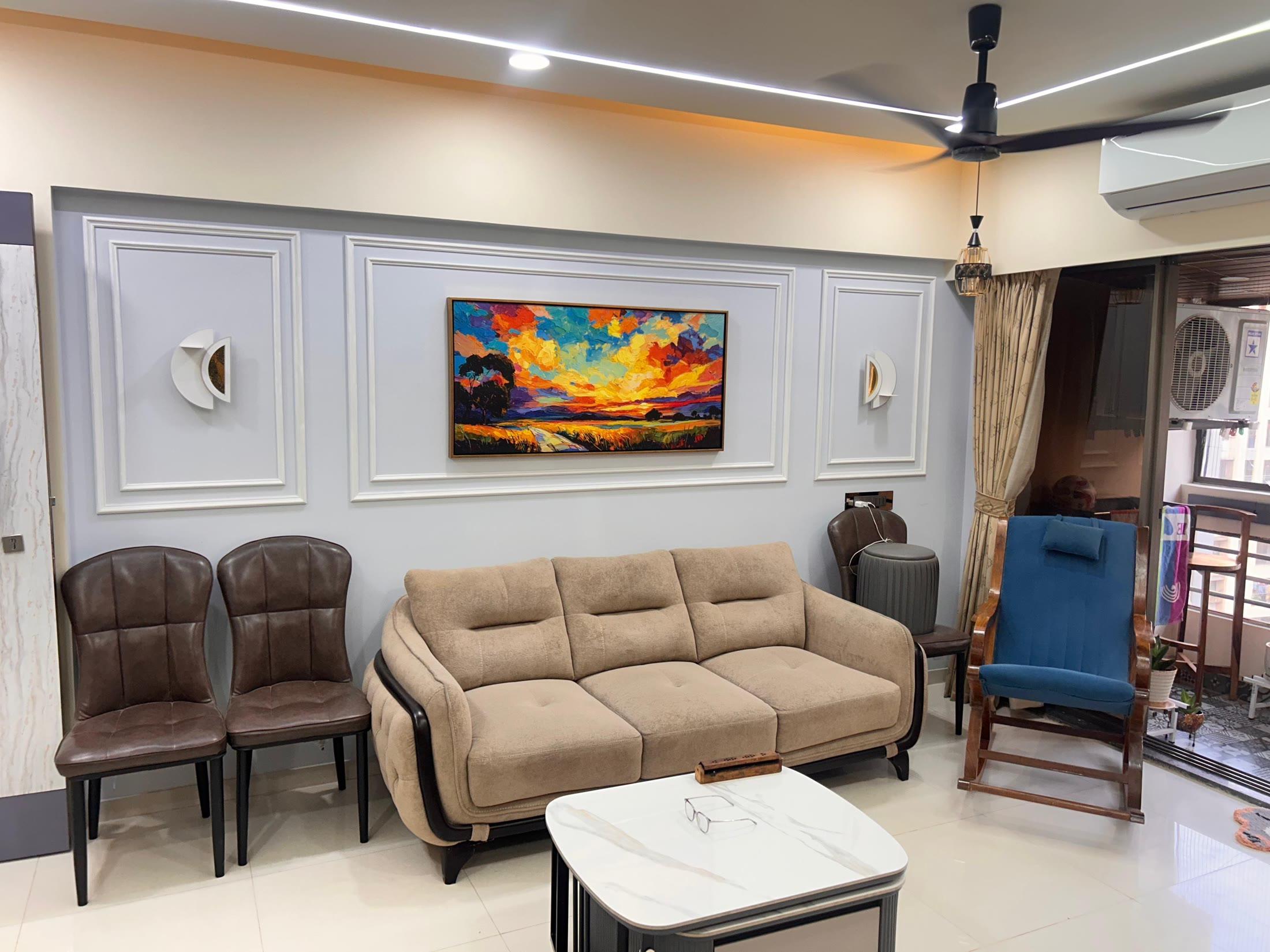 Living room with ivory panelled walls, a sunset canvas, beige sofa and blue rocking chair